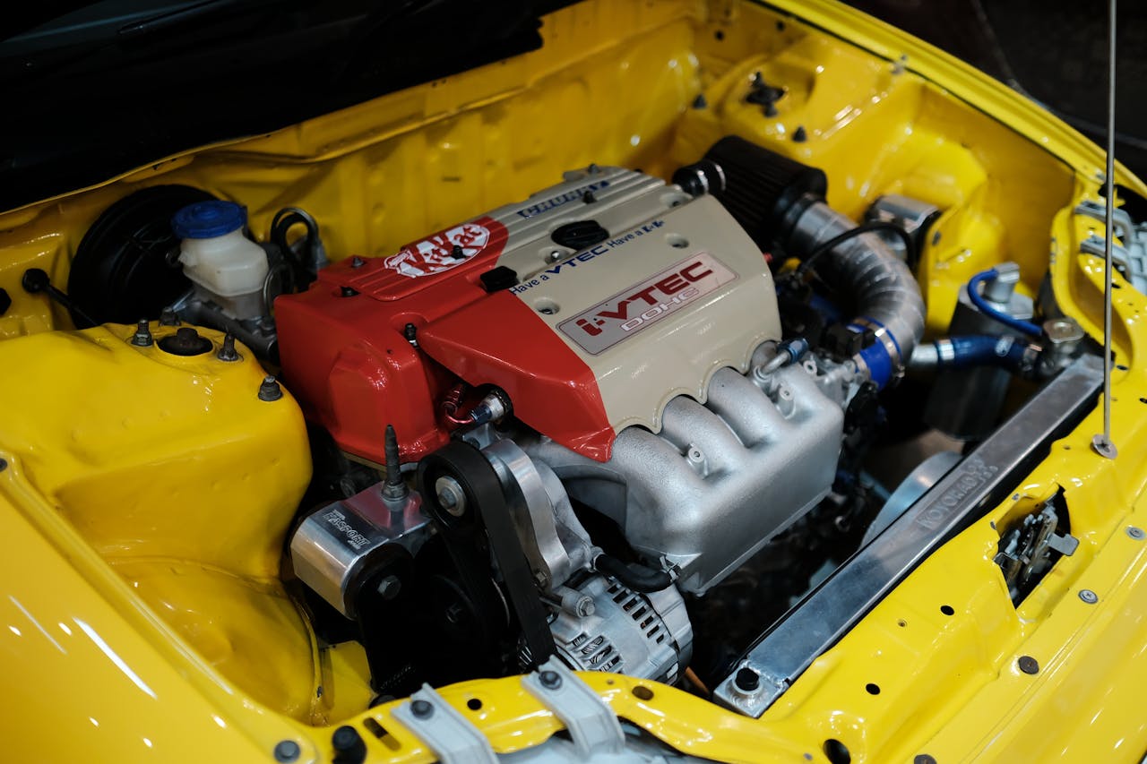 Services Close-up of a high-performance VTEC engine in a yellow Honda, showcasing automotive engineering.